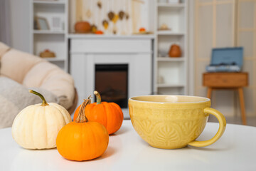 Pumpkins with mug on table in living room, closeup