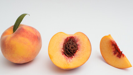 Fototapeta na wymiar Whole and cut ripe peach on white background. Ripe pinky-yellow peaches.