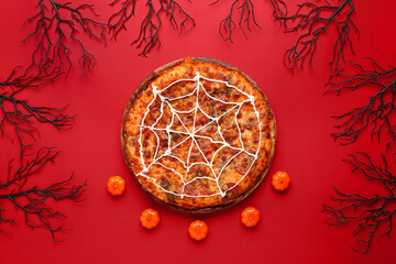 Wooden board with tasty pizza and decorations for Halloween party on red background