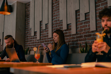 Gorgeous blonde businesswoman chatting on her phone while working remotely at the coffee bar