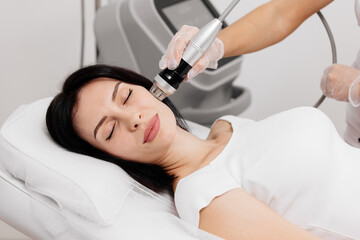 Young сaucasian woman undergoing a cosmetic procedure fractional RF lifting against a light background. Advertising concept for clean and young facial skin.