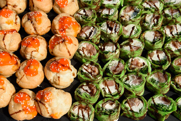 Snacks and canapes and tartlets stuffed in the assortment on the buffet table. The food is varied and appetizing for a banquet.