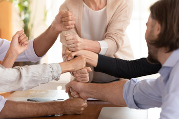 Group of businesspeople stack fists making tower enjoy engagement in funny team building activity,...