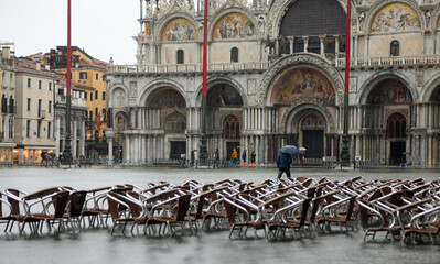 chairs tables of alfresco cafe in San Marco square in Venice during high tide completely flooded