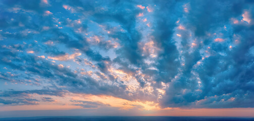 Aerial, long panoramic view of colorful, orange and blue colored streakes of   clouds on deep blue...