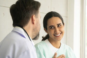 Relaxing Caucasian male physician with Hispanic female patient. The medical healthcare exam and check-up with the doctor concept.