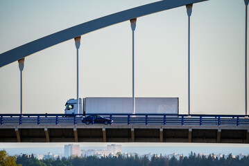Truck with refrigerated trailer driving on a suspension bridge.