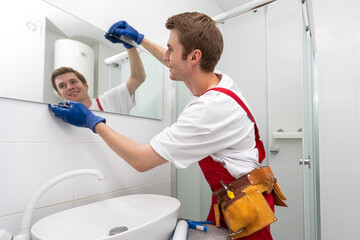Male repairman hangs the modern electronic bathroom mirror. accessories and furniture for bathrooms...