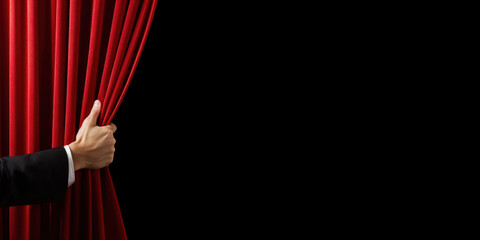 Hand open the red stage curtain. Isolated on black with copy space for text