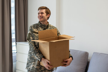 Patriotic military man in uniform keeps box in new apartments. Buying a property