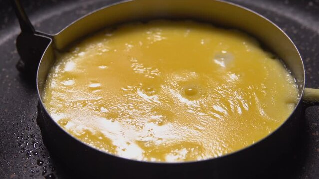 Super close-up of an egg yolk fried in mold in a frying pan