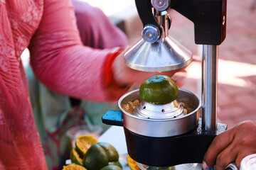 a woman uses a metal manual orange juice press