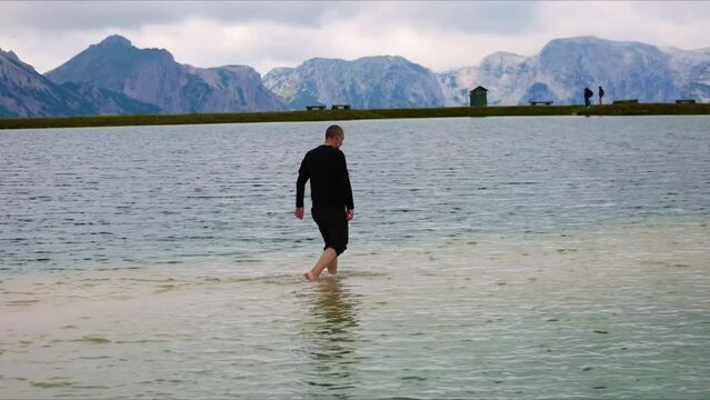 Man walk in alpine lake Schafkogelsee in Austia 
