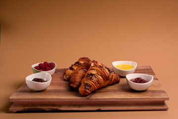 Croissants on the wooden board. Jam, chocolate, raspberries. Perfect French breakfast. Minimalistic photography. 