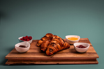 Croissants on the wooden board. Jam, chocolate, raspberries. Perfect French breakfast. Minimalistic photography. 