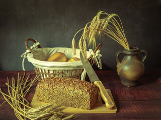 Rustic still life in antique style with bread and ears of wheat . - 651622022