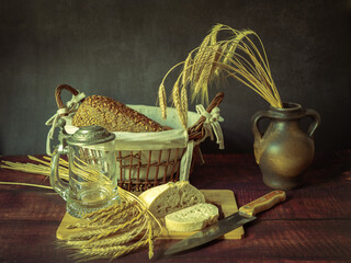 Rustic still life in antique style with bread and ears of wheat . - 651622027