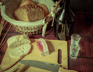 Rustic still life in antique style with bread, ears of wheat and ham and bacon. - 651622205