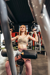 Fototapeta na wymiar Beautiful young redhead woman exercising in a spacious and modern equipped fitness gym. People and recreation concept.