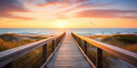 Serene sunset overlooking calm beach. Tranquil beginnings. Peaceful sunrise on ocean shore. Wooden path to paradise. Relaxing beachside boardwalk at dawn - obrazy, fototapety, plakaty