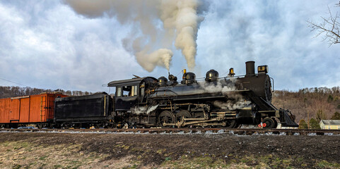 A View of a Restored Narrow Gauge Steam Locomotive Blowing Smoke and Steam on a Winters Day