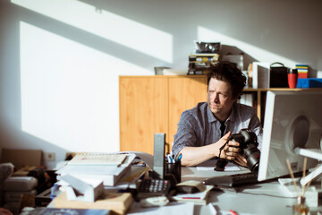 Young Caucasian male photographer stressing over work at his job in a media company office