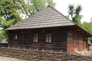 A wooden house with a pile of wood in front of it