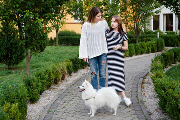 A woman and her teenage daughter walk together with a dog and talk, discuss important issues...