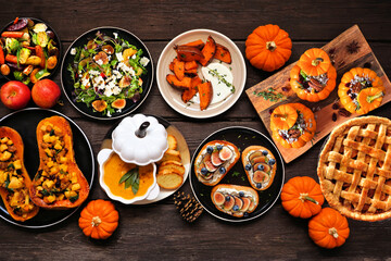 Delicious autumn meal table scene. Top view on a dark wood background. Stuffed pumpkins and squash,...