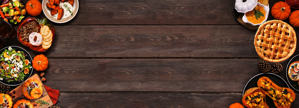 Delicious autumn meal double border. Overhead view on a dark wood banner background. Stuffed pumpkins and squash, sweet potatoes, appetizers, soup, vegetables and apple pie.