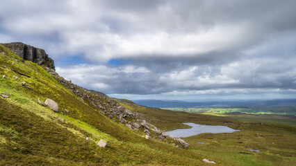 Fototapeta na wymiar Cuilcagh Mountain Park with view on cliff, rock slide and rumble leading down to small lake surrounded by bog and wetlands Fermanagh, Northern Ireland