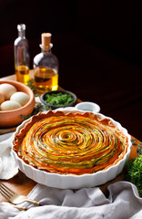 Spiral colorful vegetable tart in a casserole dish on a table, focus on  inside