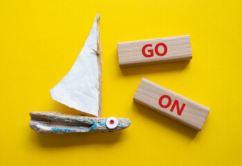 Go on symbol. Wooden blocks with words Go on. Beautiful yellow background with boat. Business and...