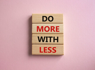 Do more with less symbol. Concept words Do more with less on wooden blocks. Beautiful pink background. Business and Do more with less concept. Copy space.