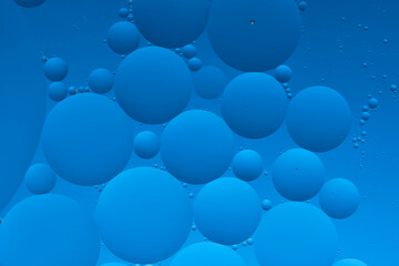 Macro photo with circles oil droplets water surface. Abstract blue background with oil bubbles.