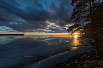 View of a frozen lake with clouds in the sky around sunset time in late winter in Finland