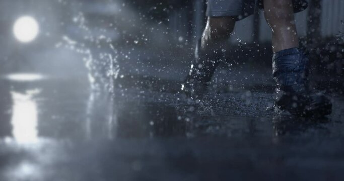 Child runs in water puddle with rain boots during rainy season in slow-motion with droplets flying in the air, nostalgic childhood concept