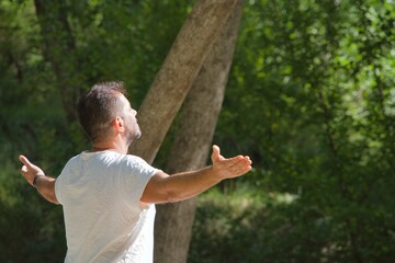 Adult Man in Nature opens his Arms while Breathing deeply pure Air