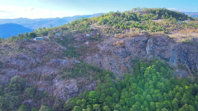 Lateral panning over a rock cliff that has some pine forest