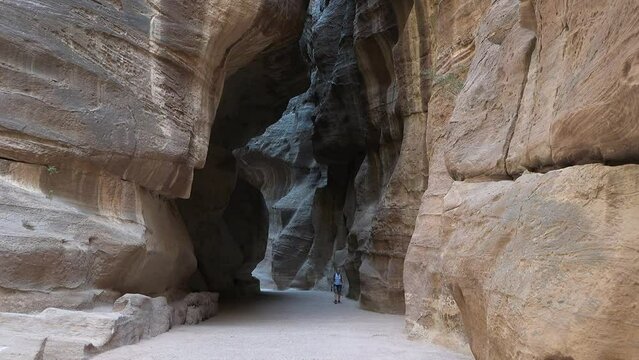 A tourist in Petra. Historical city. Unesco heritage site. A breathtaking path passing between a beautiful canyon of red rocks. Petra, Jordan. Stunning view of a man walking on the path of Petra.