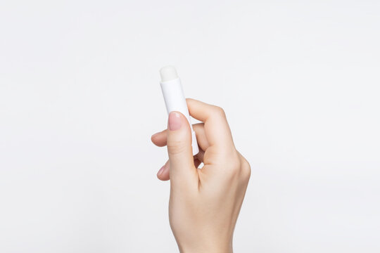 Female Hand Holding Hygienic Lip Balm On A White Background