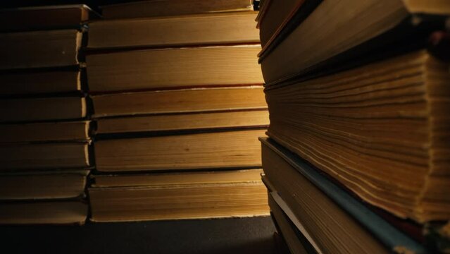 Library stack of old books, slider macro footage in antique shop, bookstore.