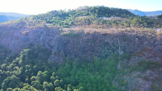Aerial circling view over a rock cliff and forest and with sunrays