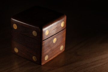 Dice, a wooden dice-shaped case for storing small dice, selective focus.