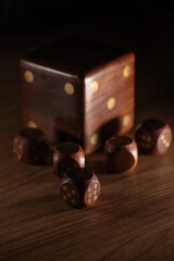 Dice, small wooden dice and a dice-shaped case, selective focus.