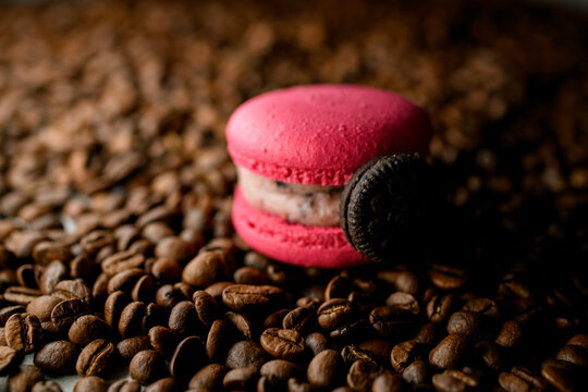 Sweet raspberry macaron dessert with oreo cookie on coffee beans background, close up view