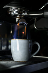 Close up view on process of pouring strong hot espresso to small white cup from professional coffee...