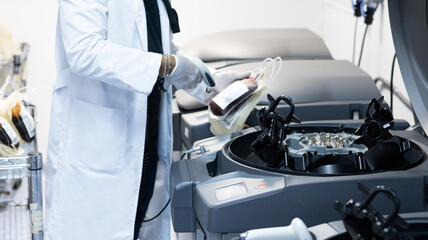 Técnico varón de aspecto latino usando guantes y escaneando una unidad de sangre entera para su fraccionamiento a través de un equipo automatizado moderno y seguro.