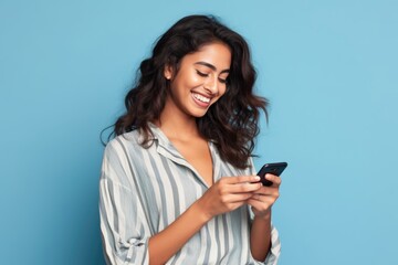 Smiling Latin Woman Shops Online with Mobile Phone on Blue Background