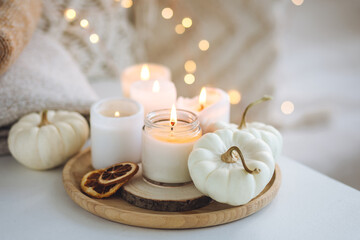 Autumn home decor with white pumpkins and burning aroma candles with sweet spicy pumpkin pie scent....